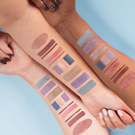 Three different arms lined up next to each other with different eye shadow pallets on each